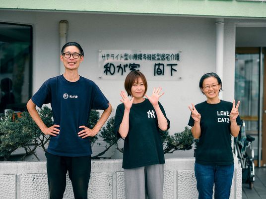 笑顔のスタッフ3人と施設入口  