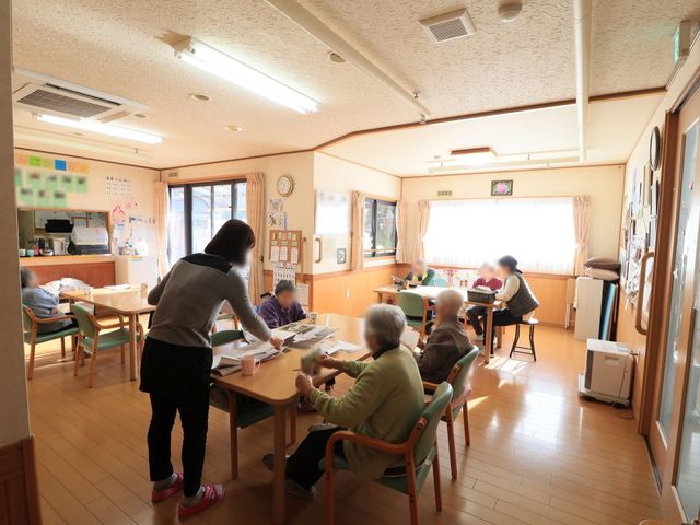 活動する人々の多目的室 食堂 明るく温かみのある多目的室で、利用者とスタッフが共に活動しており、笑顔あふれる働く環境がここにあります。
