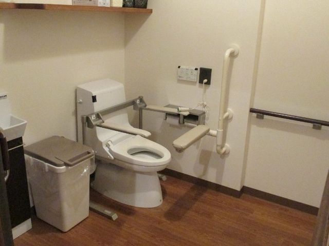 落ち着いた雰囲気のトイレ トイレ   手すりが設置された広々とした空間で、利用者が安心して使える安全な設計です。