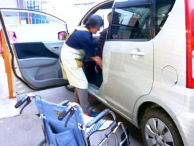 送迎準備の様子 外観 入居者が車に乗り込むサポートをしています。送迎の一環として、安全な移動を心がけています。