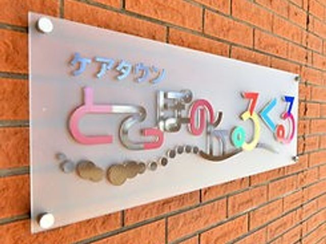 施設の名称が描かれた看板 看板 施設の名称が壁に飾られており、特徴的なデザインが目を引きます。暖かみのある色合いです。