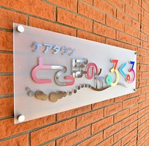 施設の名称が描かれた看板 看板 施設の名称が壁に飾られており、特徴的なデザインが目を引きます。暖かみのある色合いです。