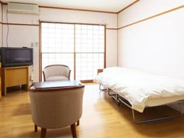 シンプルな和室 居室 広々とした和室で、心安らぐ静かな時間を過ごせます。ベッドや椅子が備え付けられています。