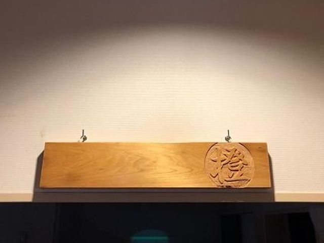 木製の看板 看板   木目の美しい木製の看板が壁面に取り付けられています。落ち着いた印象で、来訪者を迎える空間づくりが伝わります。