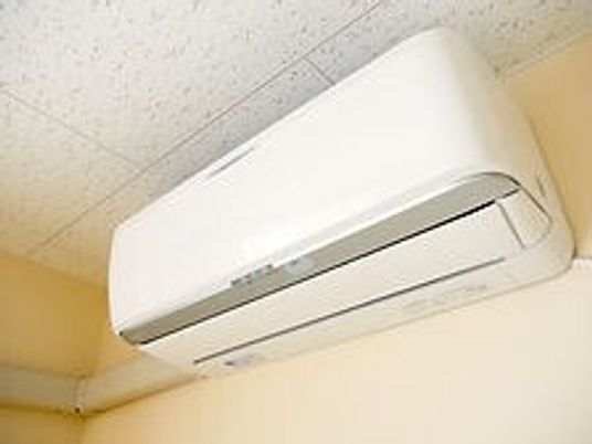 シンプルな白いエアコンを設置した居室の天井に近い壁の部分。稼働はしていない。