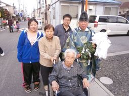 車椅子の高齢女性と家族ら