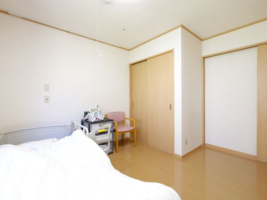 陽光が注ぎ、大きな介護ベッドが置かれている個室タイプの居室