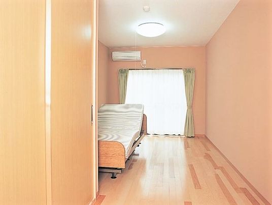 広めの空間にエアコンと介護用ベッドが付いている様子。収納付きの広めのワンルーム
