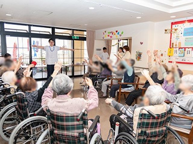 体操する人たちの室内 多目的室 多目的室では、椅子に座っての体操が可能で、参加者が和やかに過ごせる空間になっています。