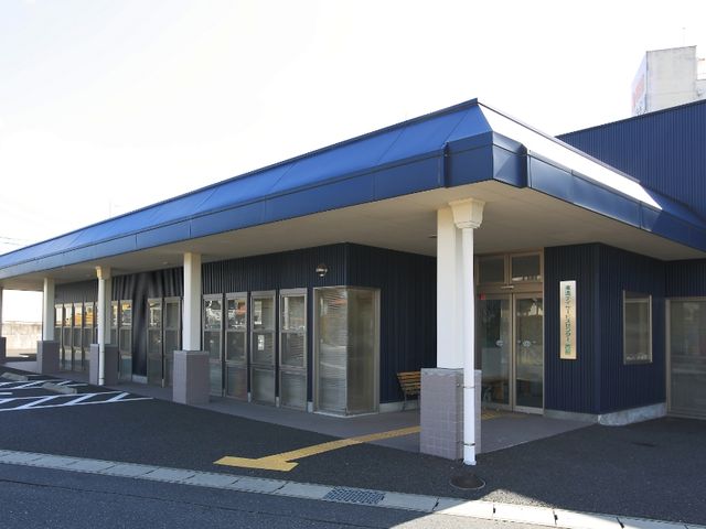 青い外壁の建物 外観 開放感あふれる明るいエントランスが特徴です。天候にかかわらず利用しやすくなっています。