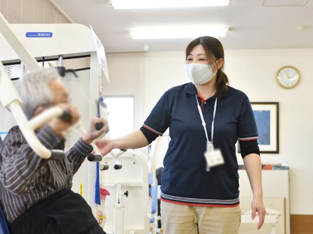機能訓練室の様子 機能訓練室 自然光が差し込む空間で、リラックスしながら身体機能の向上を目指せます。笑顔のやり取りが見られます。