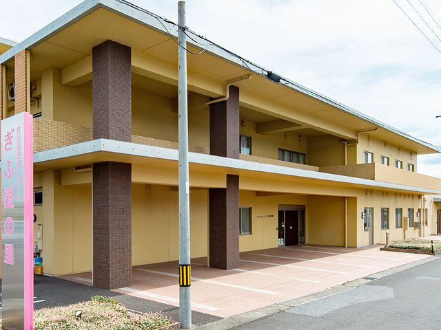 優しい色合いの建物外観 外観 やわらかい色合いの建物で、広々とした駐車スペースがあります。温かみのある雰囲気が魅力です。