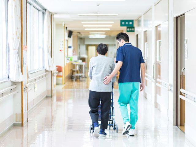 介護施設の廊下 廊下 自然光が差し込む廊下で、職員が利用者を優しくサポートしています。