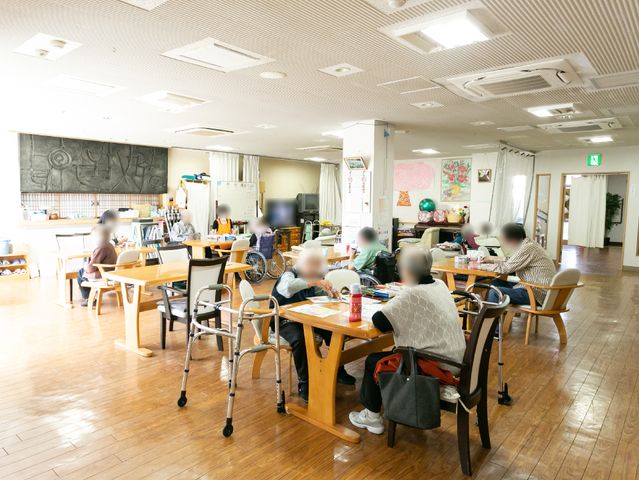 暖かい光の食堂の様子 共有スペース ゆったりとした空間で利用者が食事や交流を楽しんでいます。木のテーブルが温かみを与えています。