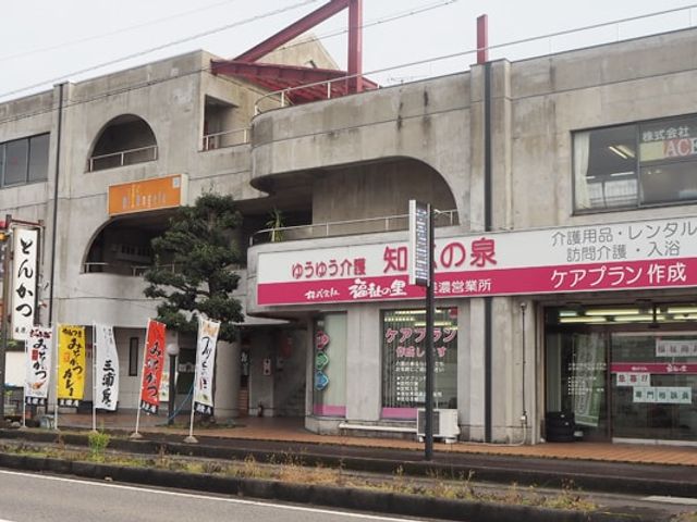 幹線道路沿いの店舗 看板 複数の看板が並ぶ外観です。介護関連サービスの案内が目立ちます。