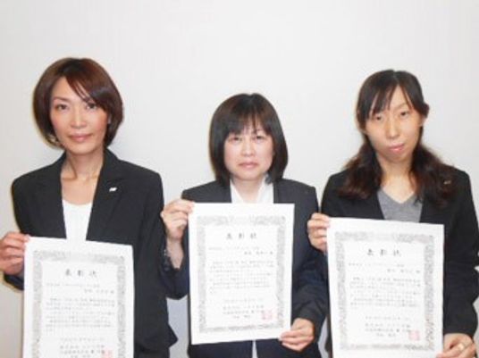 表彰状を持つ三人の女性  
