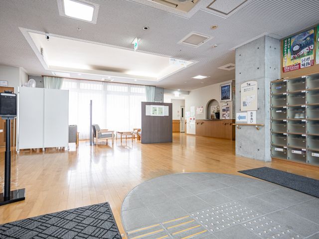 明るいロビーの入口 ロビー   自然光が差し込む明るいロビーです。広めの空間に椅子があり、来訪時の案内や待ち合わせがしやすそうです。