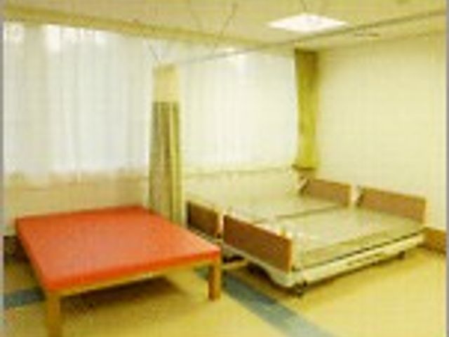 ベッドと訓練台の部屋 機能訓練室 自然光が差し込む明るい空間で、ベッドと訓練台が配置されています。快適な環境でリハビリをサポートします。