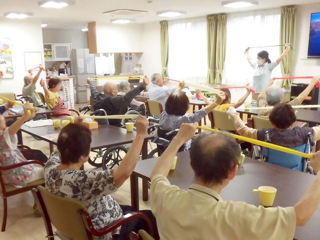 体操する人々の部屋 リビング 自然光が差し込む明るい空間で、入居者の皆様が一緒に体操を楽しんでいます。