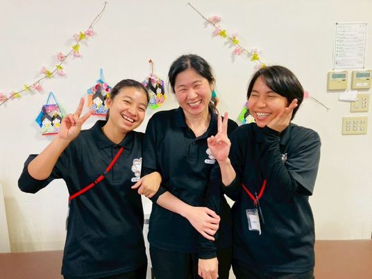 笑顔のスタッフ3人が並ぶ室内  