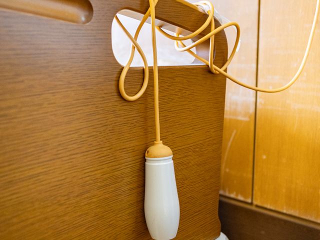 ベッド脇の呼び出し器具 居室   木目調のベッド脇に呼び出し器具が設置されています。手元で使いやすく、就業時の見守りにも配慮された空間です。