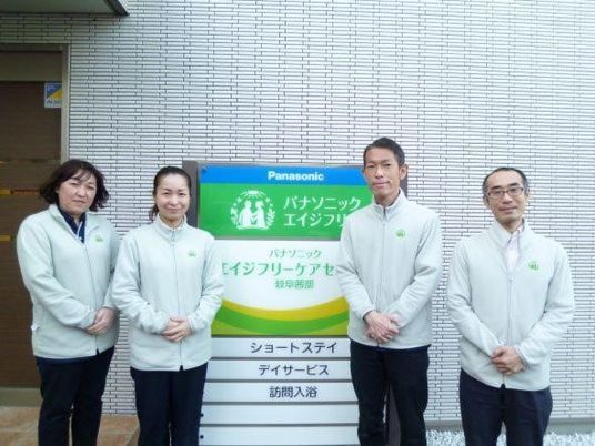 スタッフが看板前に並ぶ外観  