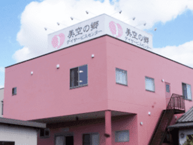 ピンク色の建物 外観 個性的なピンクの建物が目を引きます。空が晴れており、施設全体が明るく見えます。