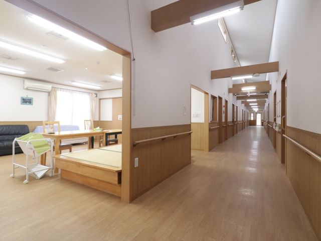 廊下に面した共有スペース 通路 木目調のあたたかみある広々とした通路は、ありのままの自分で過ごしやすい空間です。窓からは自然光が差し込み、明るく開放的な雰囲気を提供しています。