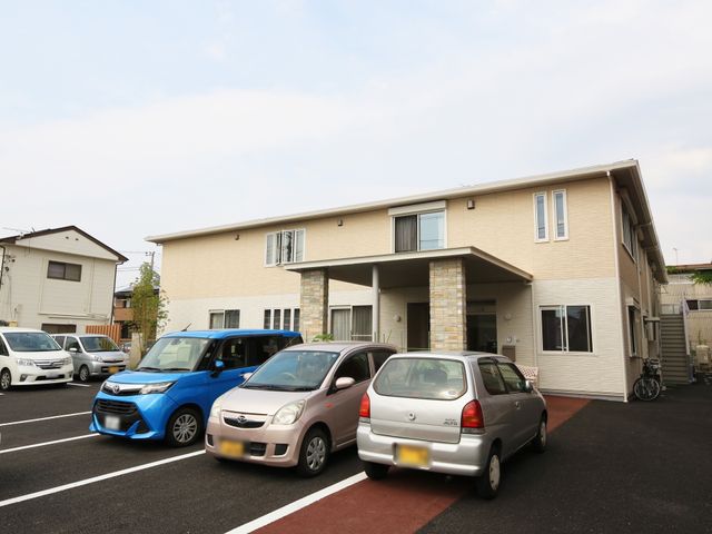 明るい外観の建物エントランス 外観 ゆったり駐車場を備えた建物の入口は、出入りがしやすい設計です。働く環境として機能性と快適性を兼ね備えています。
