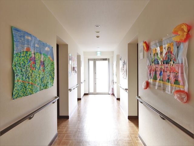 カラフルな作品の廊下 廊下 廊下がカラフルな作品で彩られ、明るい雰囲気を醸し出しています。手すりが設置されているため、歩行に不安がある方も安心です。