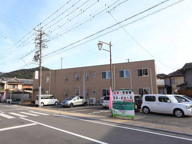 建物正面と看板 外観 車が停まる広々とした前庭のある、落ち着いた色合いの建物です。通りに面しているため、アクセスしやすく便利です。