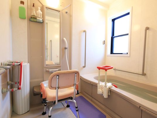 窓の付いている一人用の浴室がある。洗い場には大きな鏡と椅子が置かれ、床には滑り止めマットがある。壁には手すりが付いている。