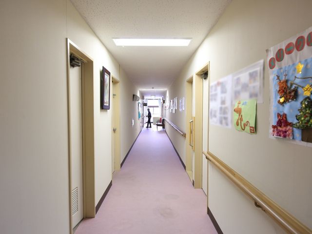 廊下の片側に手すりあり 通路  手すりが設置されている広い廊下は、安全で快適な移動が可能です。壁に飾られた作品が暖かい雰囲気を演出しています。