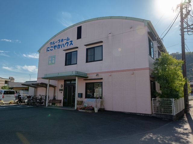 ピンクの外壁の建物正面 外観 明るく穏やかな雰囲気の建物正面は、訪れる人々を暖かく迎え入れるデザインとなっています。自然の光がたっぷりと入る開放的な入り口が特徴です。