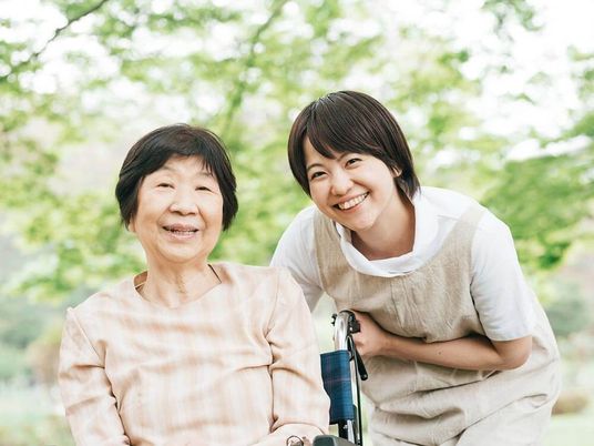 車椅子に座っている高齢女性と介助をする女性ヘルパー