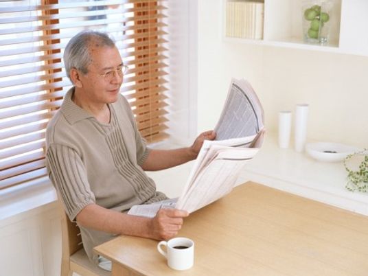 リビングで入居者様がコーヒーを飲んでいる。各種新聞が毎日配達されており、朝食前などに自由に読むことができる。
