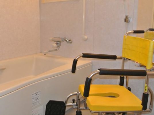 浴室は白を基調としたシンプルな設計で、背もたれのついたシャワーチェアが設置されている。浴槽内に手すりがついている。