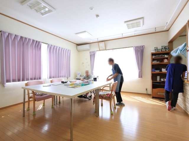 ケアの光景ダイニング 談話室 スタッフと利用者が一緒にいるダイニングです。コミュニケーションが取りやすい落ち着いた雰囲気があります。