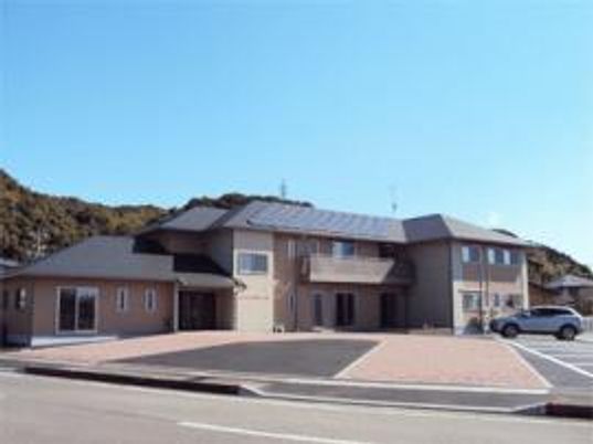 施設の写真 山に囲まれた２階建ての建物の写真。まごころホーム島田の外観写真