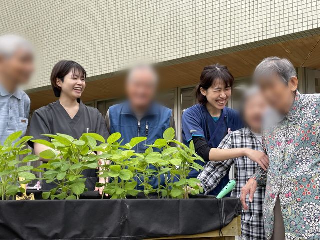 笑顔のスタッフと利用者の庭 庭 職員と利用者が一緒にガーデニングを楽しんでいます。リラックスした笑顔が印象的です。