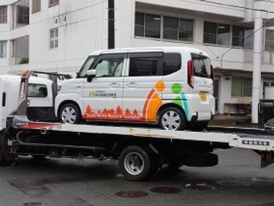 送迎車を載せた積載車と建物外観  