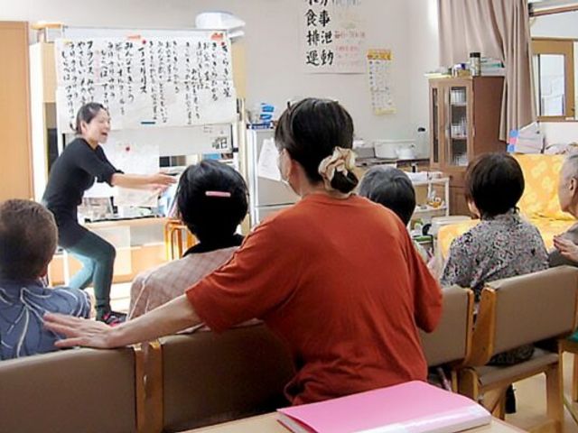 活動する人々の多目的室 多目的室 笑顔で手を振るスタッフと一緒に、様々な活動を楽しむ方々の暖かい雰囲気の場所です。