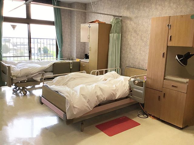 ゆったりとした居室 居室 床に赤いマットが敷かれたベッドが設置されており、寛ぎやすい空間が整っています。余裕のある間取りで、快適な生活をサポートします。