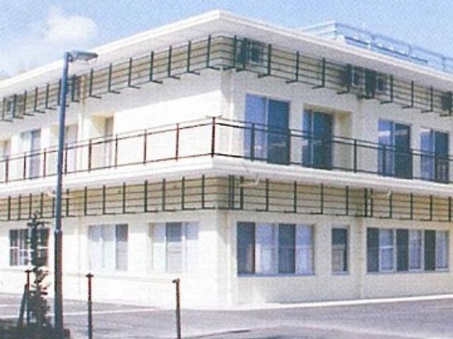 白い二階建ての建物外観 外観 現代的でシンプルなデザインの建物です。開放的な窓が設置されています。