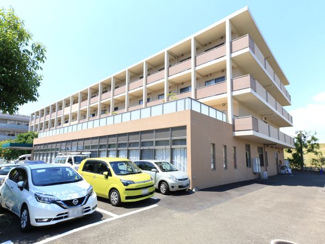 明るい外観の建物 外観 広々とした駐車場のあるモダンな建物で、働きやすい環境が整備されています。晴れた日の温かみが感じられる空間です。