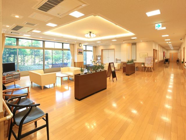 共有スペースの明るい居室 玄関ホール 広々とした快適な休憩スペースです。窓からは自然光が入り、植物の緑が目に優しい環境を提供しています。