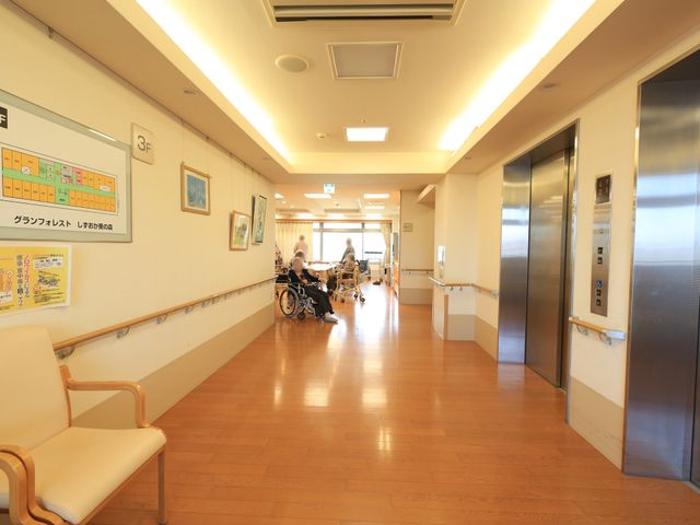 明るく広い廊下の様子 エレベーターホール ゆったりとした通路は、明るく開放的な雰囲気を提供しています。手すりが整備されており、安全に配慮された設計です。