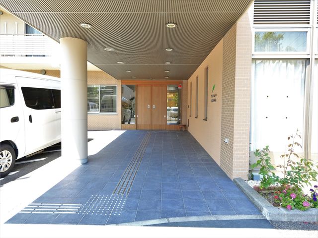 玄関と白い車 玄関 ゆったりとしたエントランスは日差しをたっぷりと取り込んでいます。車椅子でも安心のスロープが整備されていて、皆様を明るく迎え入れます。