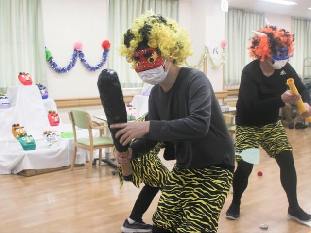 楽しい行事の様子 ダイニングルーム 参加者が鬼の仮装をして、楽しい雰囲気の中でイベントが行われています。床は木目調で温かみがあります。