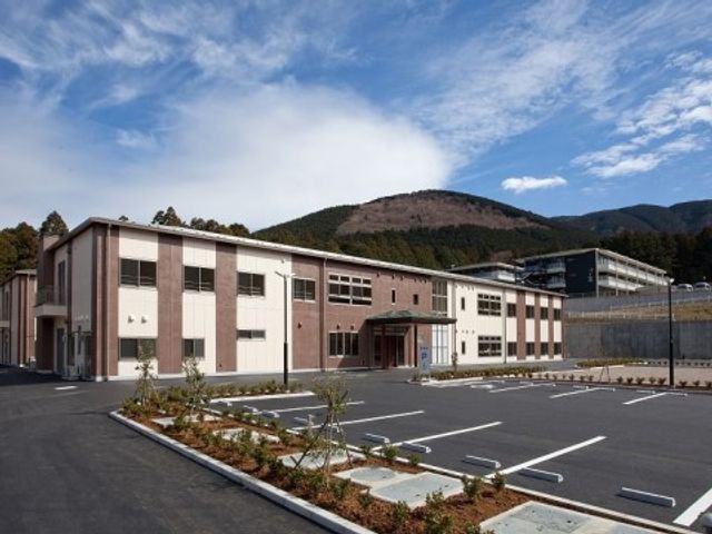 広々とした清潔な外観 建物外観 広い駐車場を完備し、清潔感のある外観から心地よい環境が感じられます。山々に囲まれ、穏やかな立地の施設での就労をご希望の方には理想的です。